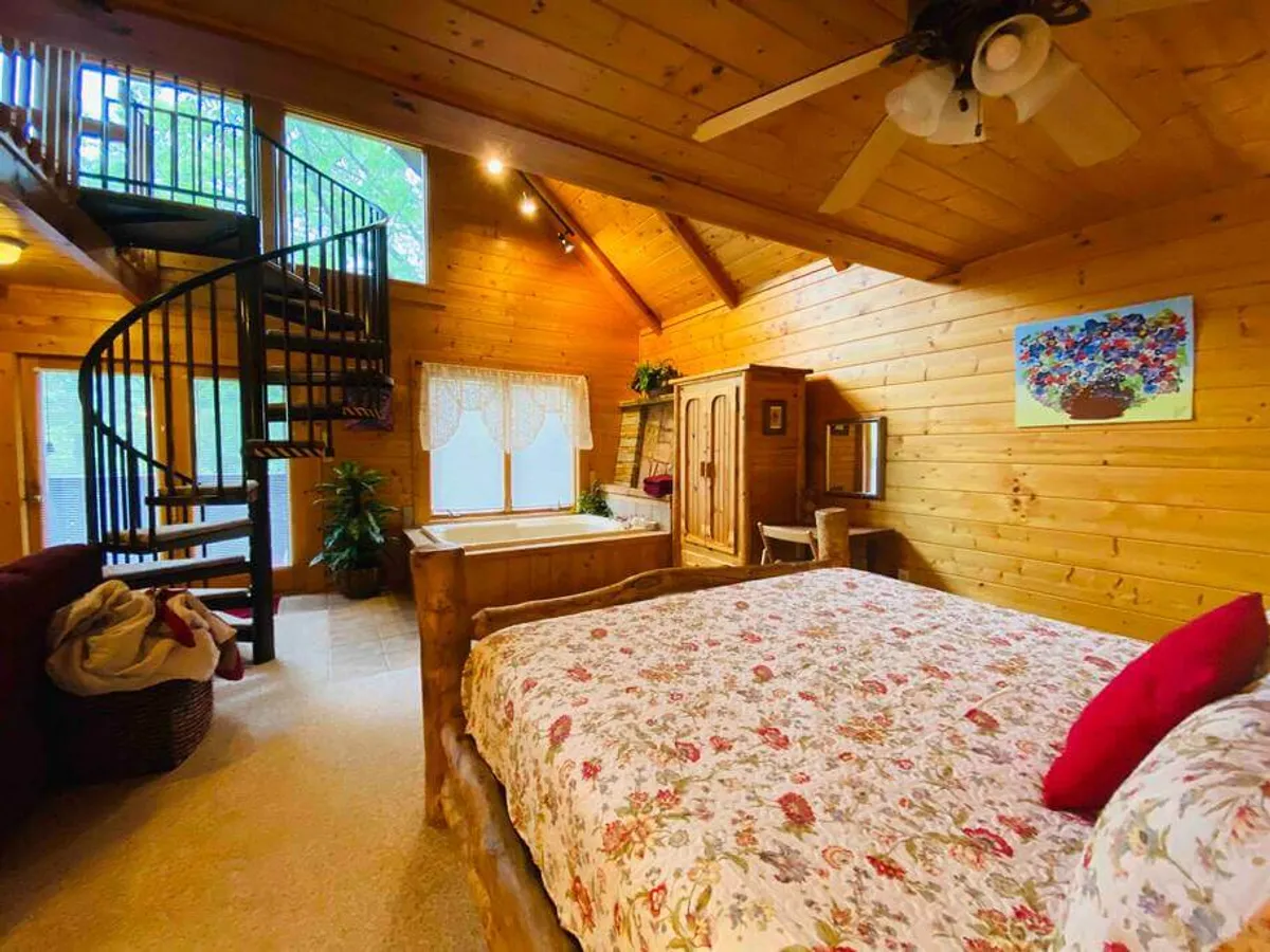 A serene bedroom featuring a large wooden bed with flower-patterned bedding, complemented by wooden furniture and a window that lets in natural light. The tranquil décor and gentle illumination create a restful, inviting atmosphere ideal for relaxation.